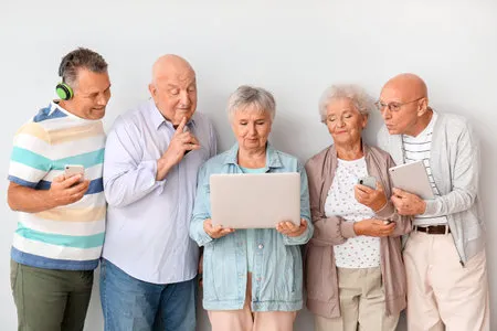 198789859-senior-people-with-different-devices-near-light-wall-in-room