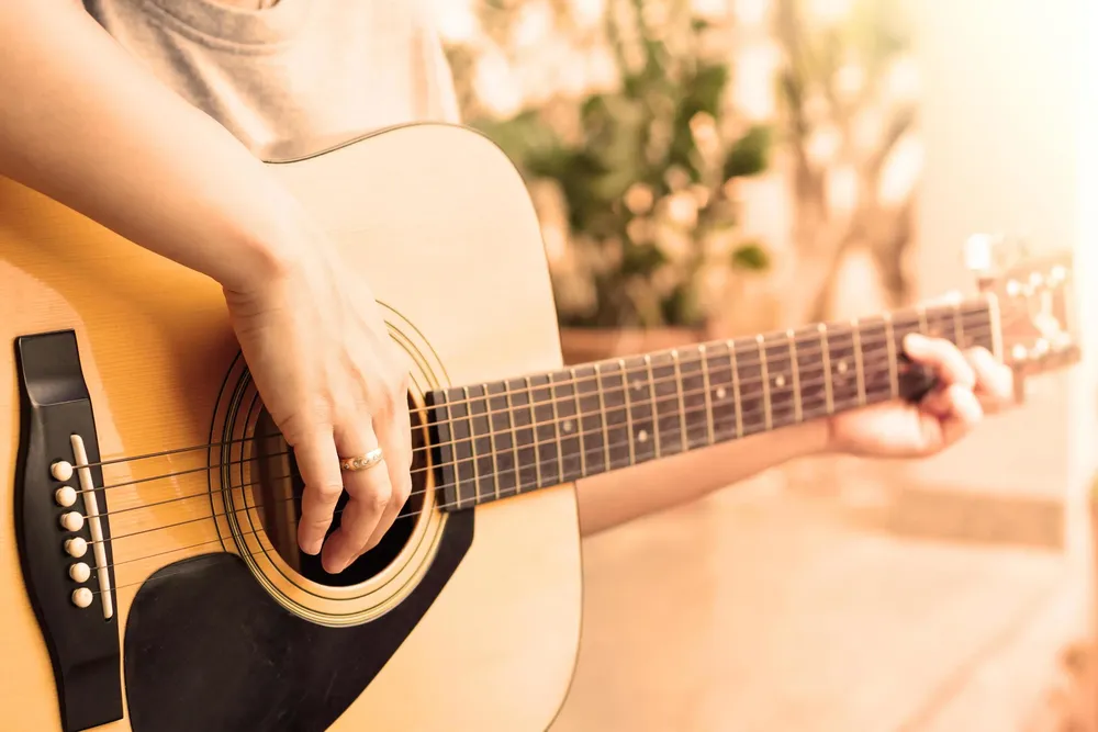 close-up-of-person-playing-an-acoustic-guitar-free-photo